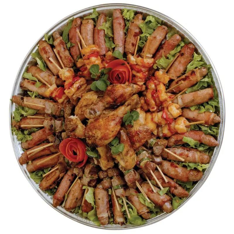 A round catering platter of grilled sausages, chicken pieces and skewers on a bed of lettuce